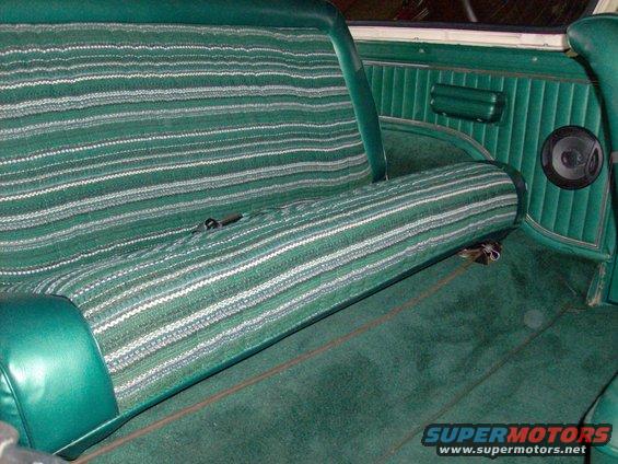 Green striped bench seat and carpet in a vehicle interior with a speaker visible on the door panel