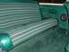 1978 Ford Bronco - The interior of a vehicle shows a green striped bench seat and matching carpet, with a speaker mounted on the door panel.