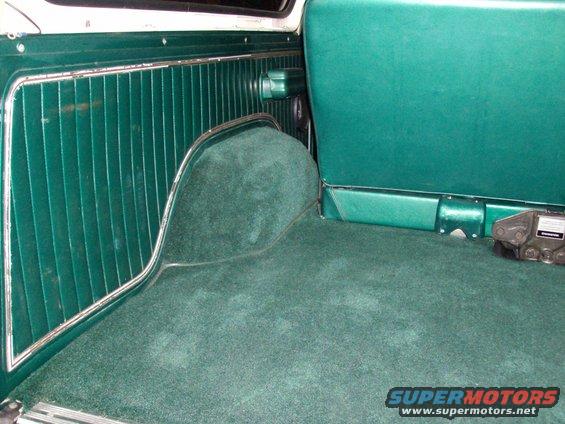 Green carpeted interior cargo area with ribbed paneling and a seat