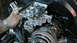 1970 Volkswagen Beetle - A person works on the carburetor of a Volkswagen Beetle engine, with a visible metal tag on the engine block.