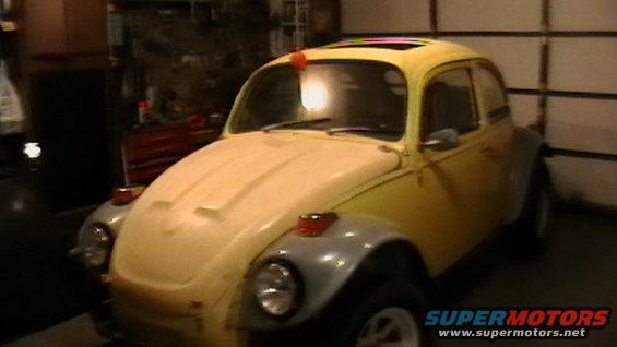 Yellow 1970 Volkswagen Beetle with a sunroof and grey fender flares, parked indoors