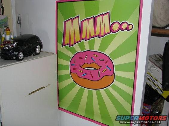 Box with pink frosted donut and green sunburst pattern, text reads "DONUT..."