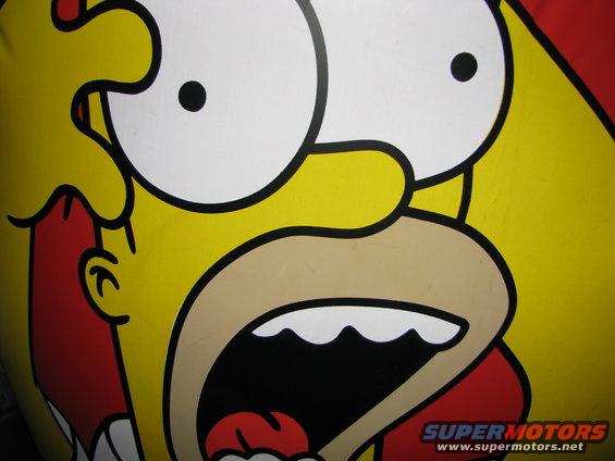 Close-up of Homer Simpson's face painted on a yellow surface, with a red shirt visible