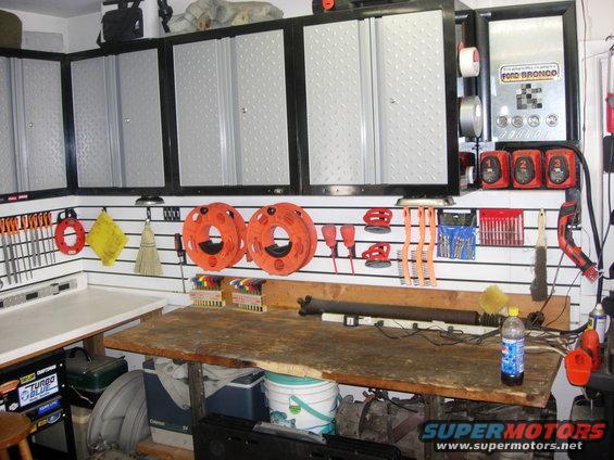Garage workbench with tool organizers, storage cabinets, and a Ford Bronco sign