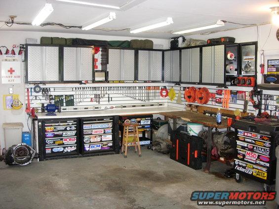 Garage workshop with tool cabinets, workbench, and parts. Some toolboxes have racing stickers