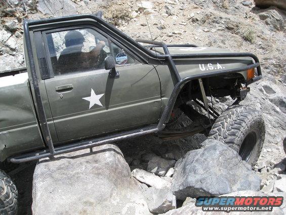 Olive green pickup truck with white star and "U.S.A." text, off-roading