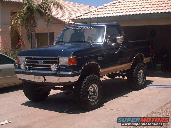 Dark blue Ford F-150 pickup truck with tan lower body trim, lifted suspension, and aftermarket wheels