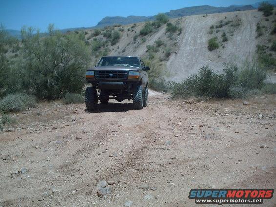 Ford F-Series truck with lifted suspension on a dirt road in a desert landscape
