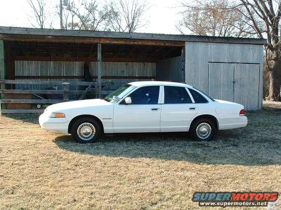 White sedan parked in front of a shed