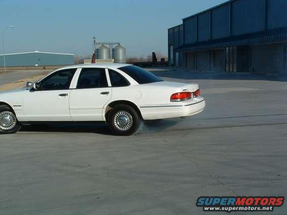 White 1995 Ford Crown Victoria doing a burnout, side view