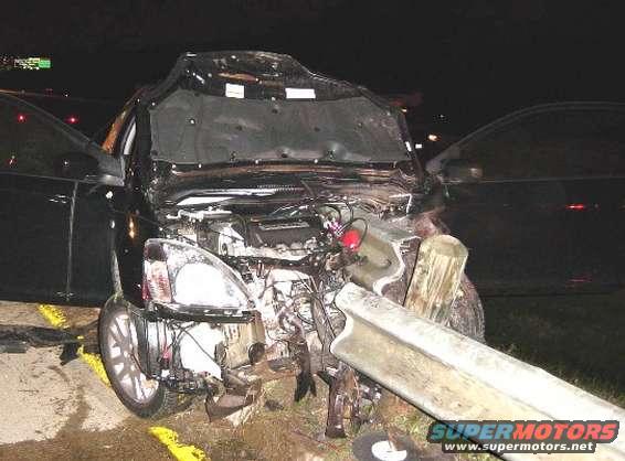 Car front end is destroyed after a crash, hood is up showing the engine