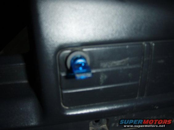 Close-up of a blue toggle switch installed in a vehicle's dashboard