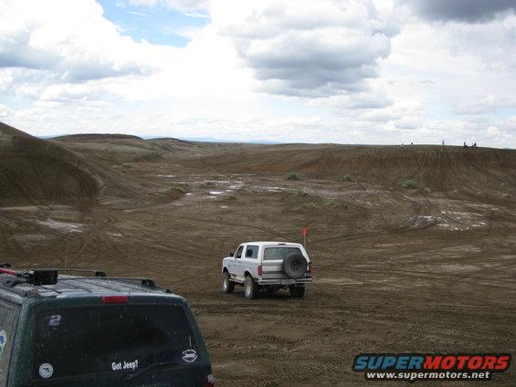 White Ford Bronco with a spare tire on the back, driving on a dirt track