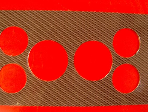 Close-up of a red dashboard with a textured gray grille and five circular cutouts