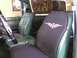 1978 Ford Bronco - Interior of a green vehicle a tribal cross seat cover and a Beatles Abbey Road poster on the rear window.