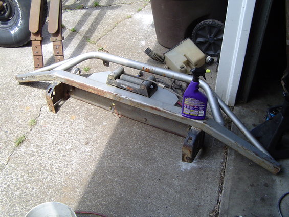 Aftermarket front bumper with winch, purple spray bottle on top. Spare tire and leaf springs visible to the left