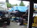 1979 Ford Bronco - Two vehicles are in a state of disassembly, with one body covered by a blue tarp, revealing exposed engines and chassis components.