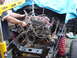1979 Ford Bronco - Mechanic using an engine hoist to remove the engine from a vehicle chassis during a repair or restoration.