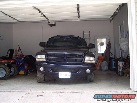 Dark blue SUV parked in a garage, front view. License plate 5CF.89S