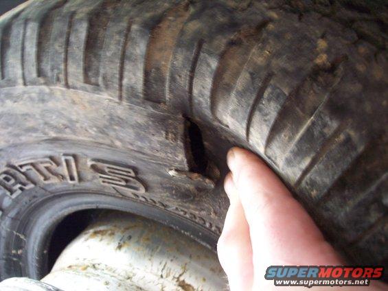 Close-up of a damaged tire with a cut in the sidewall. Text on tire reads 'RTI 3'