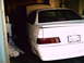 1995 Ford Taurus - The rear of a white sedan is visible, parked inside a dimly lit garage with its hood up.