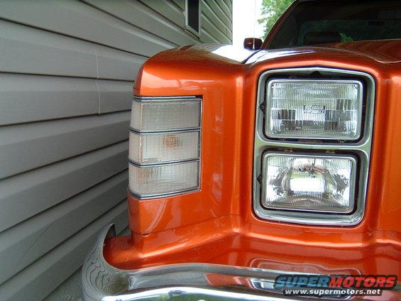 Front corner of an orange car showing stacked headlights and a triple-stacked turn signal