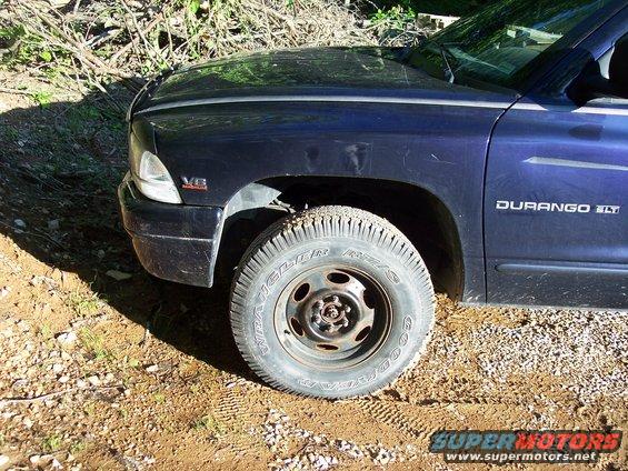 Dark blue SUV front fender and tire on dirt road