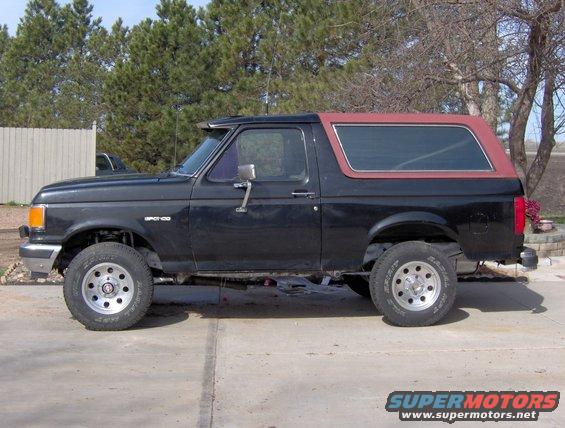 Side view of a black 1987 Ford Bronco with a red top