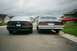 1996 Chevrolet Impala - Two sedans are parked on a street with houses in the background under a cloudy sky.