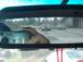 1996 Chevrolet Impala - A hand holds a digital camera, with other vehicles seen in the reflection of the rearview mirror.
