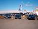 1996 Chevrolet Impala - Several sedans are parked in a lot outside a Hooters restaurant under a clear blue sky.