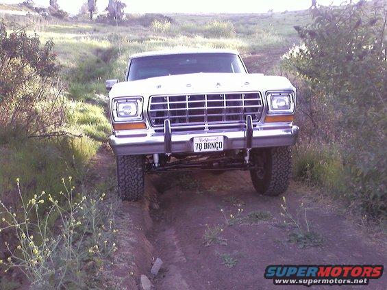 Front view of a 1978 Ford Bronco driving on a dirt path