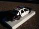1996 Chevrolet Impala - A model police car is displayed on a white platform outdoors.