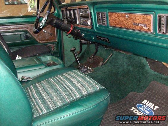 Green 1978 Ford Bronco interior with plaid seat inserts and woodgrain trim