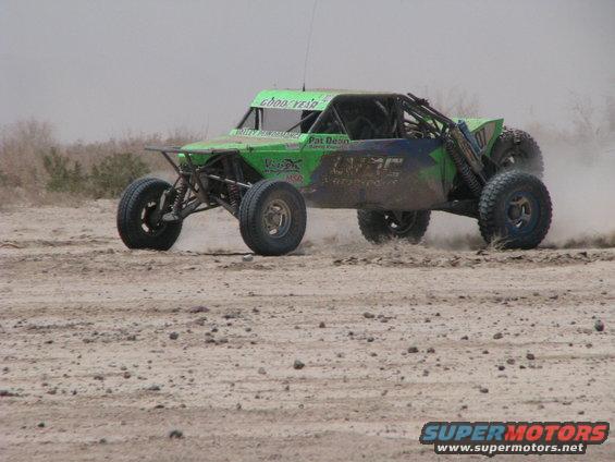 Green off-road buggy with racing decals kicking up dust