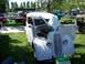 1972 Ford Ranchero - A white sedan is displayed with its hood and door open at an outdoor car show.