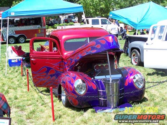 Custom hot rod pickup truck with purple and red paint, hood open, at an outdoor car show