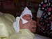 1993 Dodge 2500 - A newborn baby wearing a hospital cap and wrapped in a blanket is held by adult hands.
