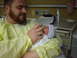 1993 Dodge 2500 - A father lovingly feeds his newborn baby with a bottle while both are dressed in hospital gowns.