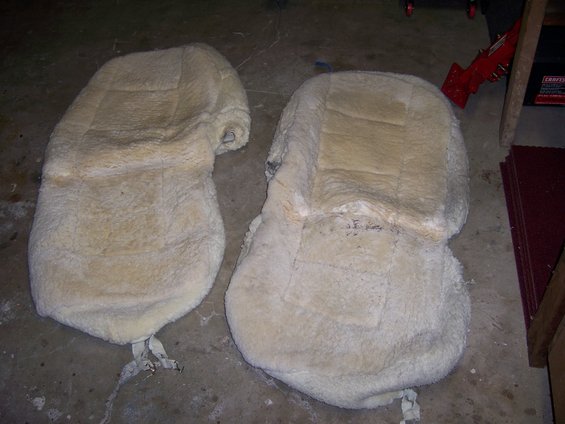 Two sheepskin seat covers laid out on a concrete floor
