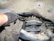 2002 Toyota Sequoia - A gloved hand uses a wrench on a suspension component. The SuperMotors.net logo is visible in the lower right corner.
