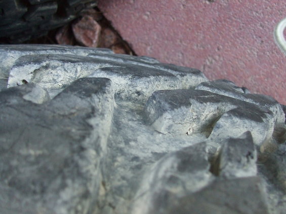 Close-up of a knobby off-road tire tread with dirt and debris