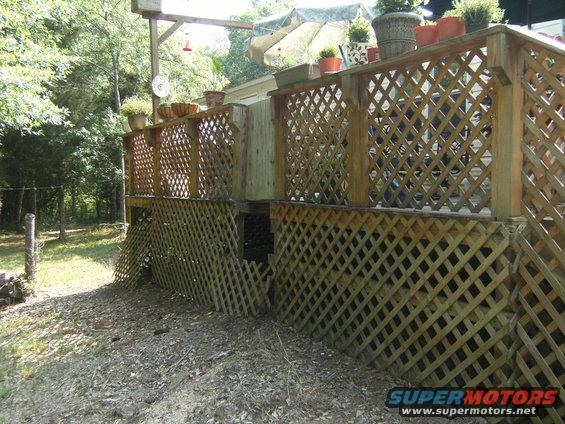 Wooden deck with lattice skirting and potted plants on top, viewed from a low angle