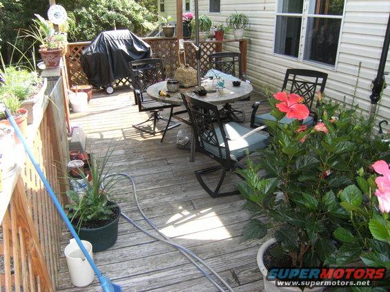 Deck scene with table, chairs, grill, and flowering plants
