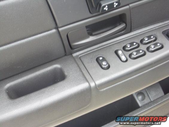 Interior door panel with power window controls and a storage cubby