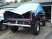 1979 Ford Bronco - A black 1979 Ford Bronco is parked in a driveway, its bed covered by a blue tarp.