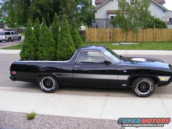 1970 Ford Ranchero, black, with trees in the bed, side view