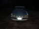 1990 Ford Mustang - A white 1990 Ford Mustang is parked outside at night, showing its front end with an aftermarket hood.