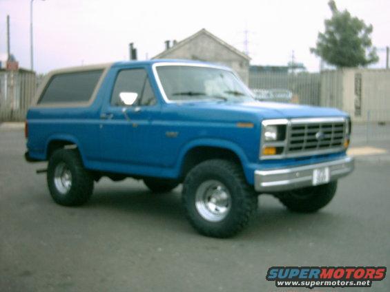 Blue 1980s Ford Bronco with tan top, 3q front view