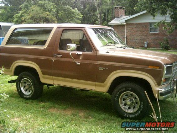 Brown 1986 Ford Bronco parked on grass with a house in the background
